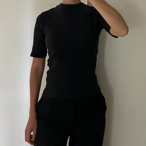 Ribbad topp med halv-polo - Svart ribbad topp från New Look med halv-polo krage i strl S.  Något urtvättad.