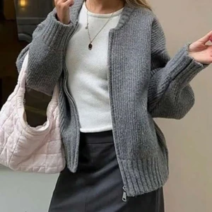 Grå stickad kofta med dragkedja - Säljer en mysig grå stickad kofta med dragkedja framtill. Perfekt för kyliga dagar, den har långa ärmar och ribbade kanter för extra komfort. Passar både till vardags och lite finare tillfällen. Ett måste i garderoben för höst och vinter!