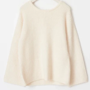 Vit stickad tröja med rosett - Superfin vit stickad tröja med en söt rosett i ryggen. Den har en lös passform och långa ärmar, perfekt för både höst och vinter. Tröjan är ribbad och ger en mysig känsla. nypris 499kr och endast använd 2 gånger 🥰