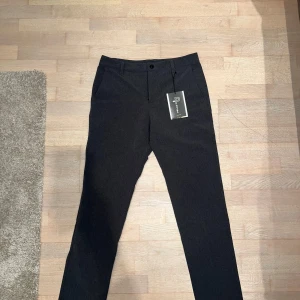 Grå fodrade golfbyxor från Pelle P - Bekväma gråa fodrade golfbyxor från Pelle P i helt nytt skick. De har en klassisk straight passform och är tillverkade i ett mjukt och bekvämt material. Perfekta for golfsäsongens kyligare tider på våren och hösten. Byxorna har en midwaist design och stängs med en knapp och dragkedja. Nypris 1400kr