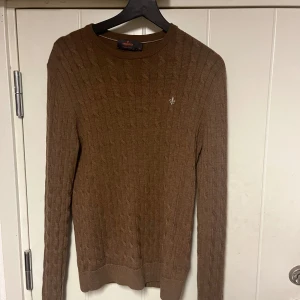 Brun kabelsticksd merinoull tröja från Morris - Säljer en snygg brun stickad tröja från Morris i storlek M men passar även S. Den är kabelstickad med 100% merinoull. Perfekt för höst och vinter, med långa ärmar och en klassisk rund hals. Skick 9/10 använd cirka 20 gånger. Köpt hos Morris hemsida för 1800.