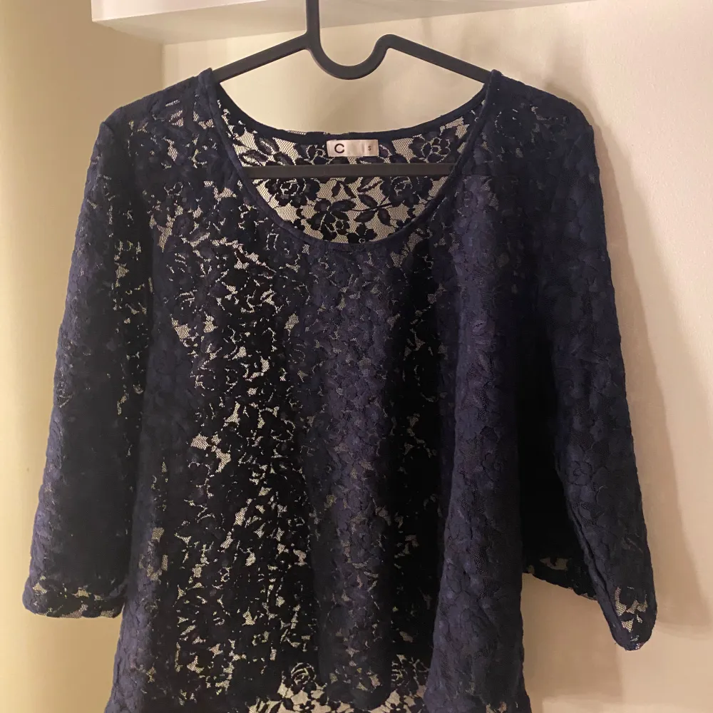 Säljer en elegant mörkblå spetsblus, Blusen har trekvartsärmar och ett vackert blommigt mönster. Perfekt för både vardag och festliga tillfällen. Den är i mycket bra skick och redo för en ny ägare!. Yläosat.