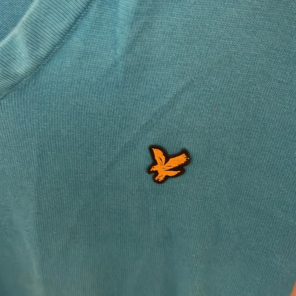 Säljer en snygg blå tröja från Lyle & Scott i storlek S. Den har en v-ringad design och ett broderat emblem på bröstet. Perfekt för både vardag och fest! 💙. Tröjor & Koftor.