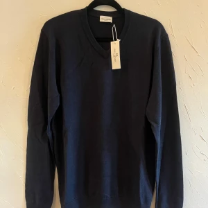 Mörkblå tröja från John Henric - Säljer en stilren mörkblå tröja från John Henric i storlek S. Tröjan har en klassisk v-ringning och är perfekt för både vardag och fest. Den är i nytt skick med etiketten kvar. Passar perfekt till höst- och vintergarderoben!