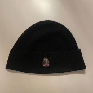Svart mössa från Parajumpers - Kond 10/10 Snygg och stilren svart mössa från Parajumpers. Perfekt för kalla dagar med sin mjuka och bekväma passform. Mössan är i nycksick 