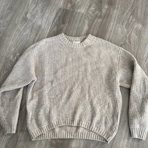 Beige stickad tröja - Säljer en supermysig beige stickad tröja i bra skick. Perfekt för höst och vinter med sin varma och bekväma design. Tröjan har långa ärmar och en rund halsringning. Passar perfekt till både jeans och kjol för en avslappnad look.