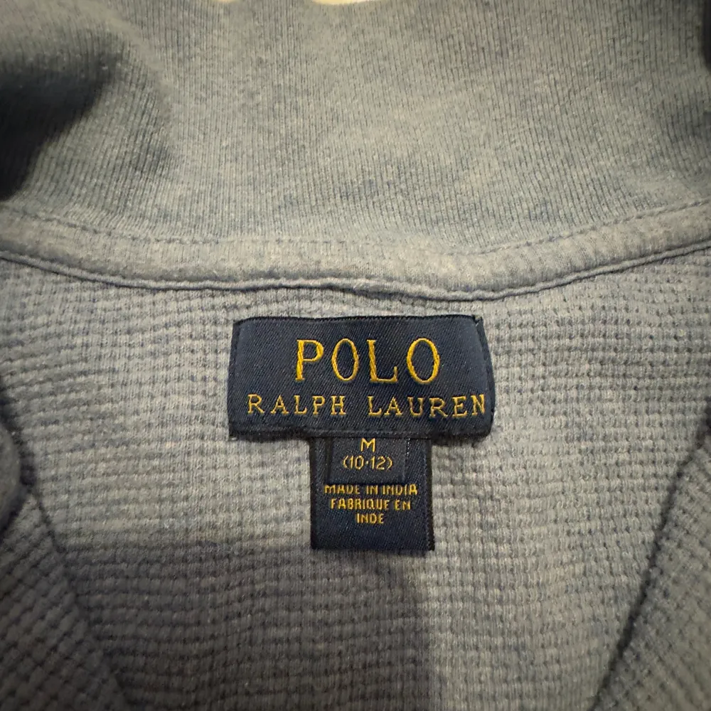 Säljer en snygg blå tröja från Polo Ralph Lauren i storlek M för barn mellan 10-12 år . Tröjan är i bomull och har en dragkedja vid halsen. Perfekt för både höst och vår, med en stilren design och det klassiska logotypbroderiet på bröstet. Skön och stilren för alla tillfällen!. Tröjor & Koftor.