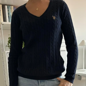 Mörkblå ribbad tröja med v-ringning - Säljer en snygg mörkblå tröja med v-ringning och ribbad struktur. Tröjan är från us polo och är nästan aldrig använd!