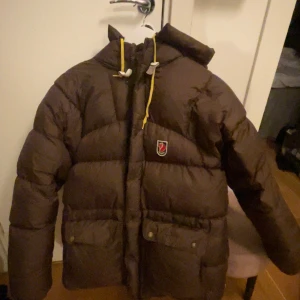 Brun dunjacka från Fjällräven - Säljer nu min super fina bruna fjällräven jacka i storlek xs (stor i storleken) . Den är i fint skick förutom några fläckar på framsidan av jackan och en reva på baksidan av armen på jackan men inget man tänker på. (Se bilder 3 och 4)