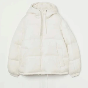 Vit pufferjacka Hm - Säljer en snygg vit pufferjacka med dragkedja och huva. Jackan har en loose passform och är perfekt för kyliga dagar. Den har långa ärmar och justerbar dragsko i nederkant för extra värme.