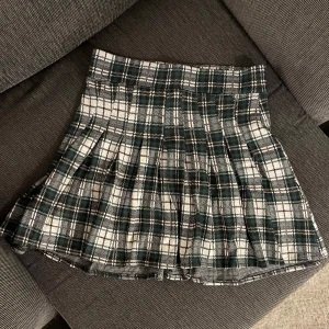Rutig kjol  - Snygg rutig kjol i grönt, svart och vitt. Kjolen har en klassisk plisserad design som ger en stilren look. Super fin✨☺️