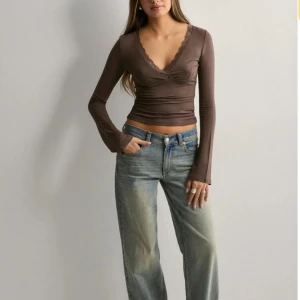 Brun omlottopp med spetsdetaljer - Snygg brun omlottopp med v-ringning och spetsdetaljer längs kanten. Använd 1 gång! 