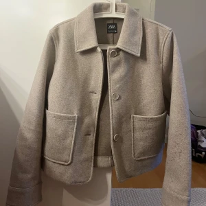 Beige kappa från Zara - Snygg beige kappa från Zara. Perfekt för en stilren look. Passar bra till både vardag och mer uppklädda tillfällen.