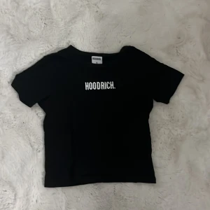 Svart kortärmad topp från Hoodrich - Snygg svart topp från Hoodrich med korta ärmar och tryck framtill. Perfekt för en avslappnad stil.