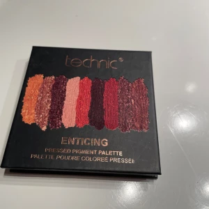 Enticing Pressed Pigment Palette från Technic - Denna palett från Technic innehåller nio pressade pigment i varma toner som orange, brons och rödbrun. Perfekt för att skapa både vardagliga och dramatiska ögonlooks. Paletten har en inbyggd spegel för enkel applicering. Använd några gånger men har fortfarande mycket produkt kvar!