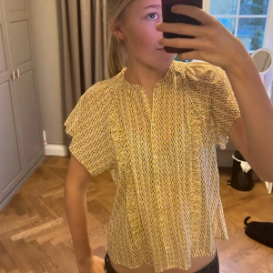 Mönstrad blus från Zadig & Voltaire - Säljer en snygg mönstrad blus från Zadig & Voltaire i gult, vitt och svart och rosa . Blusen har korta ärmar och en avslappnad passform med en liten volangdetalj vid halsen. Perfekt för en trendig look!så unik 