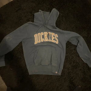 Mörkblå hoodie från Dickies - Säljer en mörkblå hoodie från Dickies med stor logga på bröstet. Tröjan har en klassisk känguruficka och justerbar huva med dragsko. Perfekt för en avslappnad stil.