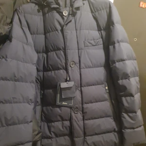 Mörkblå dunjacka från Herno - Säljer en snygg mörkblå dunjacka från Herno i nytt skick. Jackan är lång och quiltad med knappar och dragkedja framtill. Perfekt för höst och vinter med sin stilrena design och varma material. Passar både till vardags och lite finare tillfällen. New pris 10299
