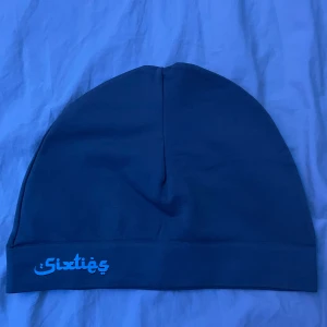 Sixties Mössa - Snygg blå mössa från Sixties med en enkel design. Perfekt för att hålla värmen under kyliga dagar. 