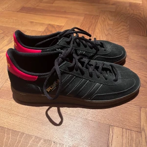 Svart/Röd Adidas Spezial storlek 42 - Adidas Spezial nypirs 1200kr. Använt dem 1 gång men behöver tyvärr sälja pga fel storlek.