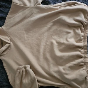 Beige hoodie - Säljer en mysig beige hoodie med långa ärmar och elastiska muddar. Perfekt för kyliga dagar och avslappnade stunder. Huvan ger extra värme och stil.