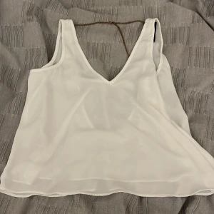 Vit ärmlös linnetopp - En väldigt fin vit topp som tyvärr är lite för stor för mig! Den har även som en guldig kedja där bak på ryggen vilket är väldigt fint!