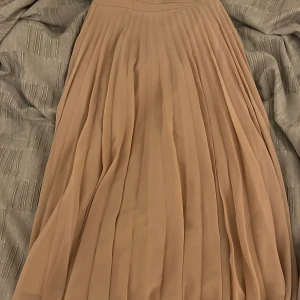 Gammelrosa plisserad kjol - Plisserad kjol, den är insydd i midjan så jag skulle säga att det är mer en 32 än en 34.