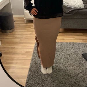 Beige ribbad kjol från Giorgia - Snygg beige långkjol från Giorgia i ribbat material. Kjolen har en slits på sidan som ger extra rörelsefrihet. Väldigt mjukt och stretchigt material. Använd 1 gång!
