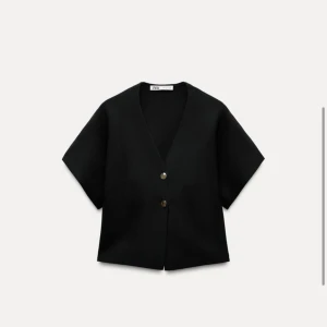 Svart v-ringad väst från Zara - Snygg svart v-ringad väst från Zara med korta ärmar och guld knappar framtill. Perfekt för en stilren look.