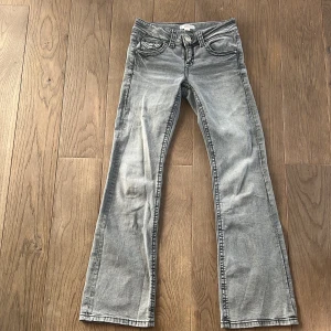 Grå bootcut jeans - Snygga grå bootcut jeans med klassisk femficksdesign och knappgylf. Perfekta för en avslappnad stil. Jeansen har små fläckar på låret från en läppolja men vi tror att den försvinner med fläckborttagning. 