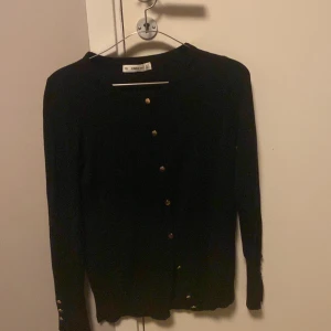 Svart kofta från Zara - Säljer en stilren svart kofta från Zara med knappar framtill. Perfekt för lager-på-lager och passar till många olika outfits. Koftan har långa ärmar och en klassisk design.