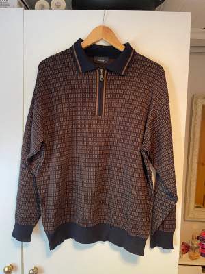 En mönstrad tröja i bruna och mörkblåa toner. Storlek: M. 