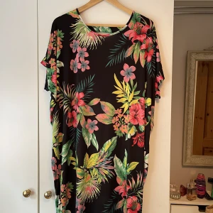 Blommönstrad Klänning - Klänning med blommönster. Urringningen är baktill. Lite använd. Storlek: One Size. 