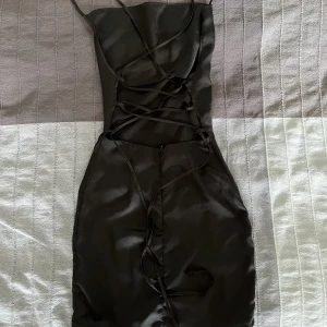 Miniklänning  - Svart miniklänning med snygg ringning och snörning i ryggen. Använd 1 gång