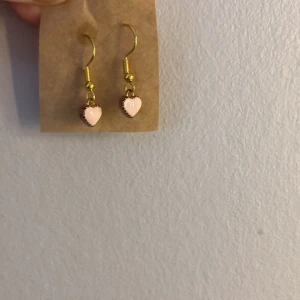 Örhängen - 3 par örhängen. Ett par med rosa hjärtan, ett par med silvriga smileys och ett par med lila smileys.