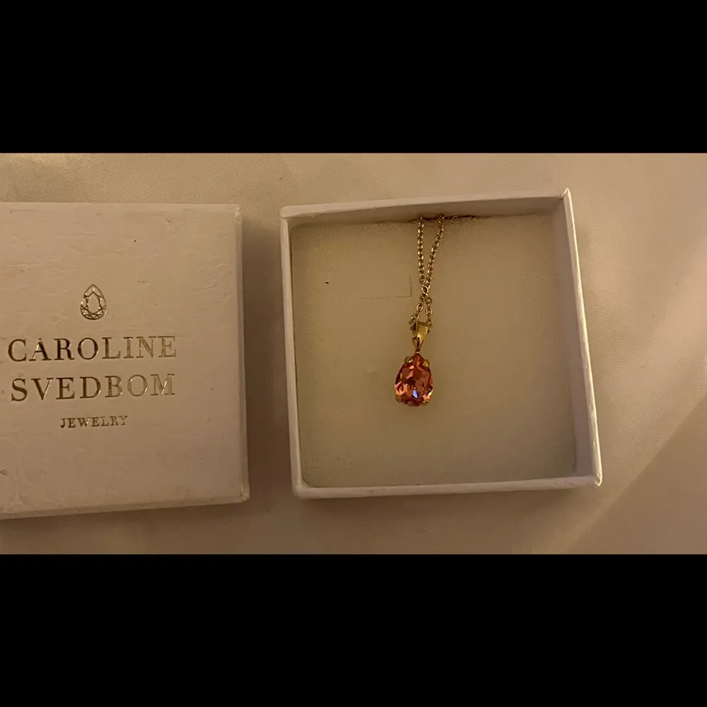 Halsband i ”guld” med rosa sten från Caroline Svedbom.  Halsbandet heter ”Petite drop necklace” - se halsbandets längd på bild tre (text från hemsidan).  Inköpspris 595:- Mitt pris 430:-. Accessoarer.