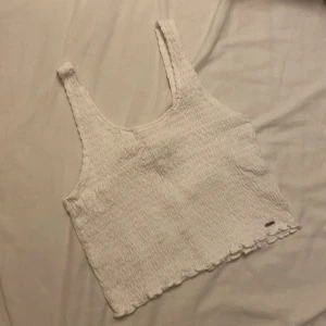 Topp från Hollister - Säljer denna snygga toppen från Hollister. I fint skick, använd ett fåtal gånger. Storlek L, passar som S/M. Croppad 