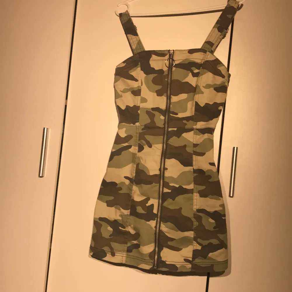 En väldigt kort klänning med militärmönster och även dragkedja på hela framsidan. . Klänningar.