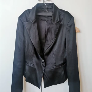 Kavaj - Svart glansig kavaj, kort blazer. Sitter som en Small 