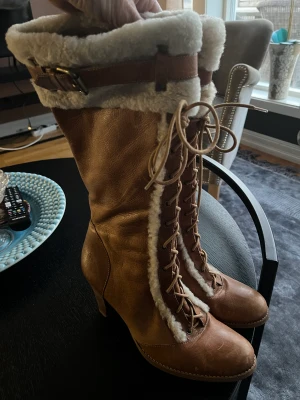 Stövlar från Brasilien  - Snygga stövlar från Brasilien men skinn och fårskinn , dragkedja , höjd totalt ca 41 klackhöjd ca 8 m vrist omkrets 34cm ,bra klackar använts ett fåtal gånger , färgen är cognac med ljus Fårpäls 