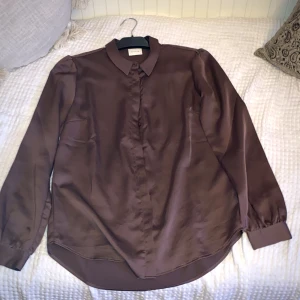 Satin-blus - Mörkrosa? Från Vila i strl 34, men skulle nog passa upp till strl M. Använd endast ett fåtal gånger, skick gott som ny!