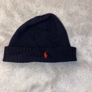 Ralph Lauren mössa - Mörkblå Polo Ralph Lauren mössa i one size. Den är för liten för mig men passar nog ett lite mindre huvud. Skick 9/10 knappt använd bara klippt bort en lapp i mössan som jag tyckte var i vägen.