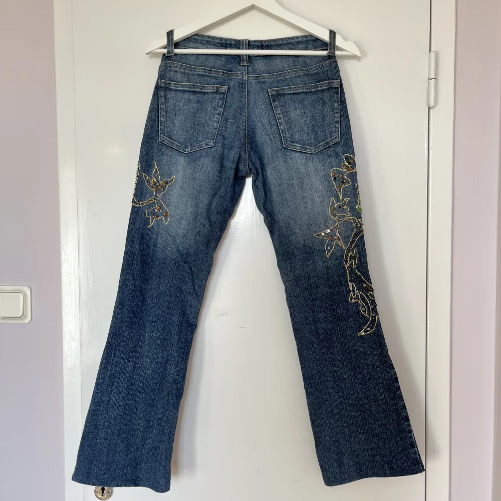 Blå jeans med strass, guldtråd, pärlor, rhinestones och paljetter från Rosa & Rosa. Utsvängda och lågmidjade. Fint skick. Innerbenslängd ca 72cm, Grenhöjd ca 21cm, midjemått ca 76cm. Jag är S och 175cm lång och de är för små på mig. . Jeans & Byxor.