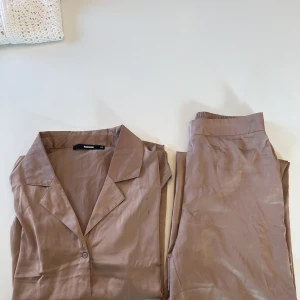 Fin ny pyjamas  - Fin och mysig pyjamas i lite metallisk guldrosa färg. Använd endast 4 gånger och därav helt nyskick. Är inte alls lika skrynklig som den ser ut på bilden. Innan den skickas tvättas den såklart ordentligt.  nypris ca 600