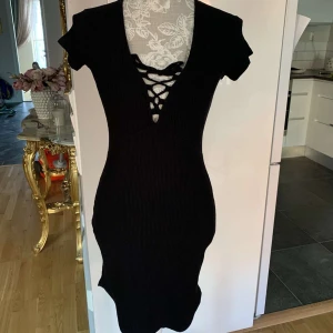 Svart tight klänning  - Kort Klänning från Gina Tricot i storlek S. Med fin snör detalj i mitten. Använd bara en gång. För 150kr