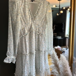 Blommig klänning  - Superfin vit klänning med blåa och gula blommor från VeroModa i storlek M. Aldrig använd. 