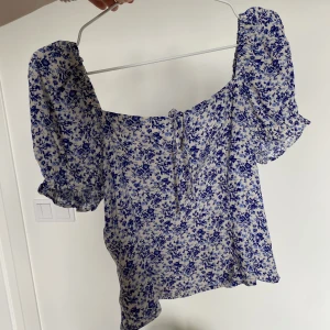 Blommig topp från h&m - Superfin sommartopp med blå blommor från h&m. Den är helt ny, säljer på grund av att den inte kommer till användning. 