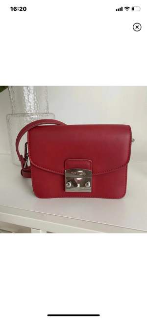 Sparsamt använd väska från märket dDon Donna. Jättefin röd färg med silvrigt lås samt 2 fack inuti. 