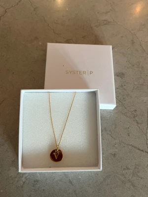 Syster P halsband ”V” - Halsband från Styster P med en ”V” berlock, guldpleterat silver. Fint skick! 