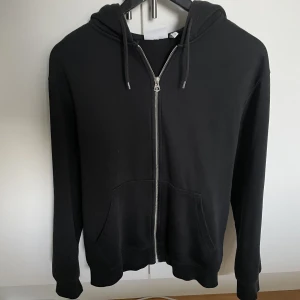 Svart zip-hoodie weekday - Svart ziphoodie från weekday i bra skick. Storleken är XS men den är ganska stor i storleken.